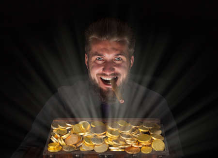 Attractive business man with a gold chest full of goldの写真素材