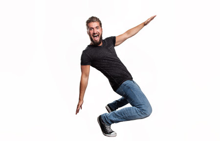Portrait of an attractive man who is pretending to drive on a skateboard in front of a white...