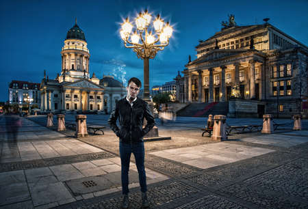 Attractive man is smoking a cigarette in Berlin in the eveningの写真素材