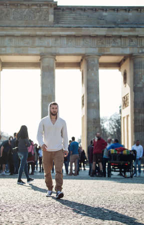 Attractive man is standing in front of the brandenburg gate in berlinの写真素材