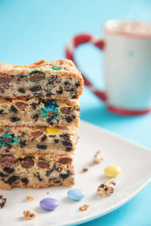 Fresh cake with smarties and a coffee on a turquoise backgroundの写真素材