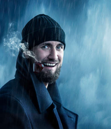 Attractive man smoking a pipe in the rainの写真素材