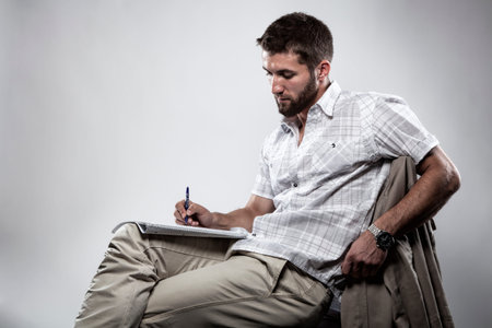 Attractive man is writing on paper