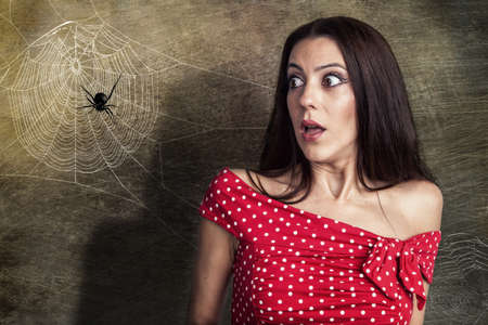 Beautiful woman is shocked to a spider next to her faceの写真素材
