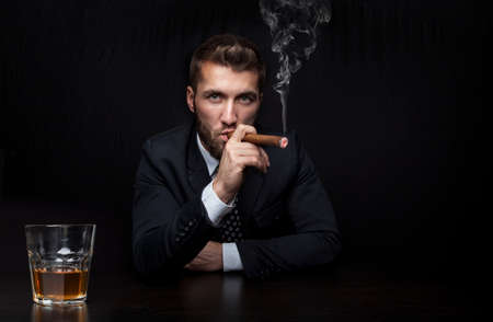 Attractive business man with a cigar and a drinkの写真素材