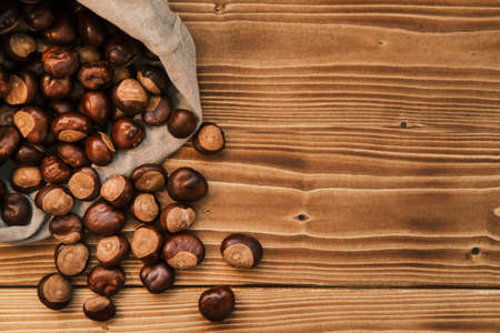 Vertical shot of chestnut in the linen bag on a wooden tableの写真素材