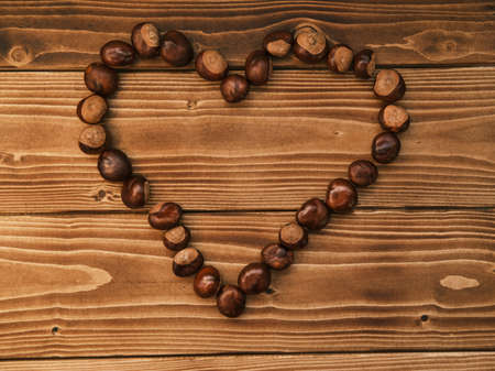 Close up shot of chestnut side by side forming a heart on a wooden tableの写真素材
