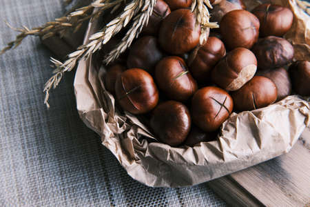 Vertical close up shot of cooked chestnut on the paper bag on a wooden tableの写真素材