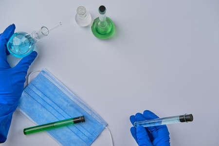 Scientist holding flask and tube at laboratory, closeup. Solution chemistry. Antivirus solution. Blue and green liquidの写真素材