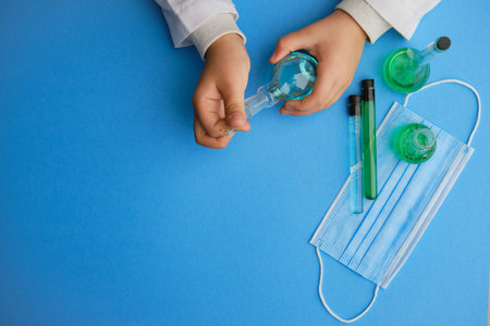 Kid holding flask and glass tube at laboratory, closeup. Solution chemistry. Antivirus solution....