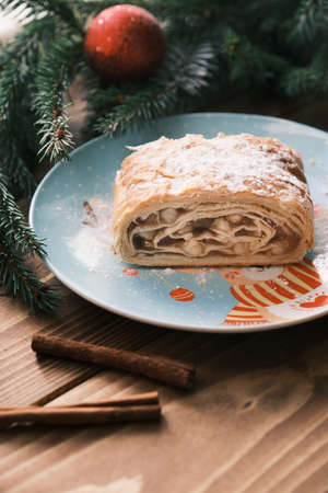 Closeup of a strudel on a Christmas plate near cinnamon sticks. Christmas breakfastの写真素材