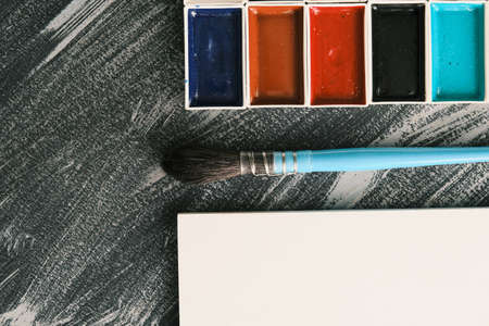 White sketchbook, squirrel brush, and watercolor paints with copy space, top view, daylight. Artist workspace conceptの写真素材