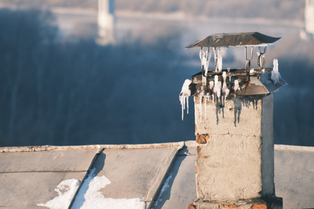 Smoking chimney on a roof top covered with iceの写真素材