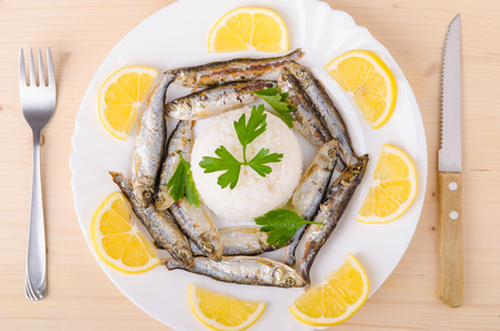 Fresh smelt on the plate decorated with rice, parsley and lemonの写真素材