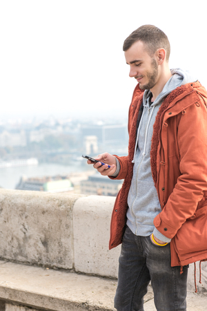 Young male smiling and using smarthphone on the street.の写真素材