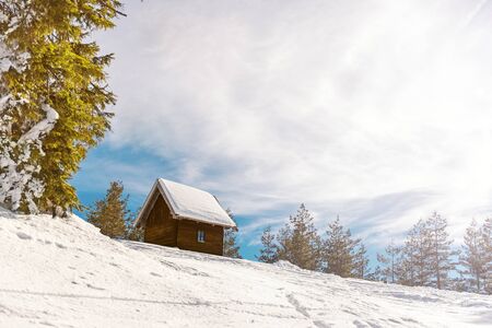 Small wooden house on he mountain covered with snow, Direct sunlight with lens flare from the right side of the frame. Copy spaceの写真素材