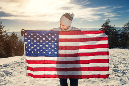 Winter scene, young man holding USA flag with spreaded hands. Copy space