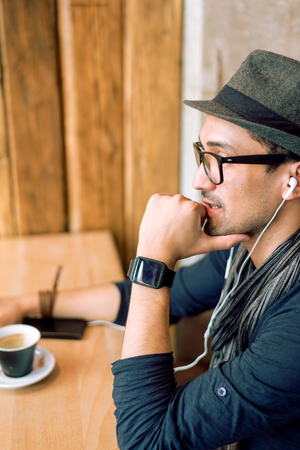 Enjoying some relaxing music and drinking coffee in the coffee bar. Selective focus. Profile shot. Toned image.の写真素材