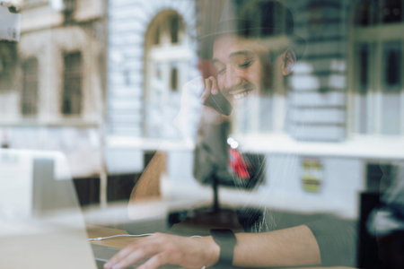 Fashionable and stylish young man talking on the phone, relaxing with coffee, music and internet...