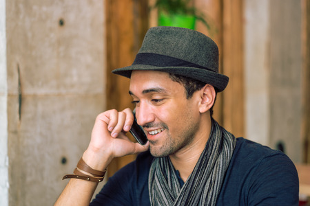 Portrait of the young and fashionable man talking on the phone. Selective focus. Narrow depth of field.Toned image.の写真素材