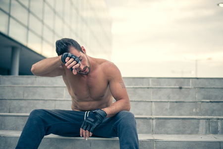 Young man relaxing and wiping sweat from his face after very heavy workout. Selective focus.の写真素材