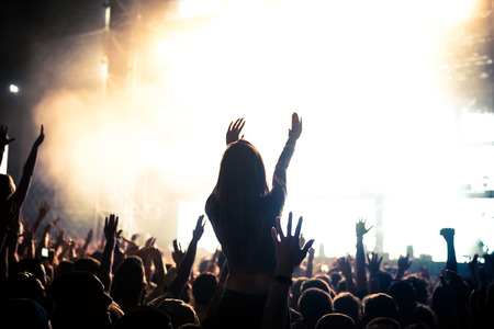 A crowd of people celebrating and partying with their hands in the air to an awesome Dj. High ISO grainy image.の写真素材