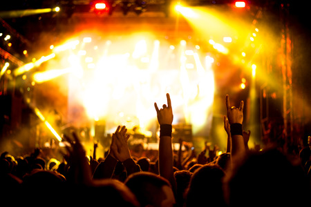 A crowd of people celebrating and partying with their hands in the air to an awesome Dj. High ISO grainy image.の写真素材