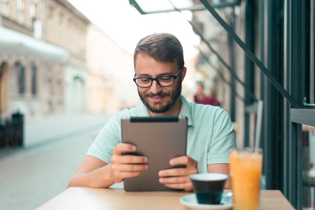 A young man working on a digital tablet in a restaurant.の写真素材
