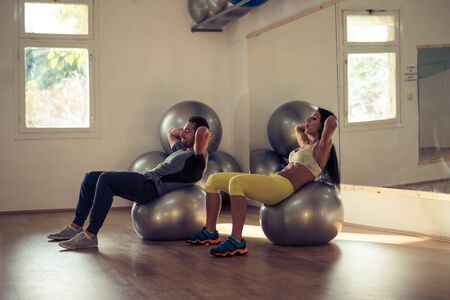 Young couple working on the exercise balls at the gym.の写真素材