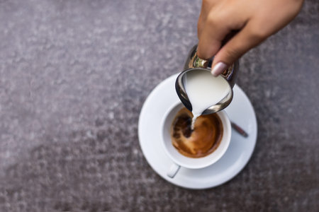 Cropped shot of a handsome women preparing coffee. Selective focus on the milk.の写真素材