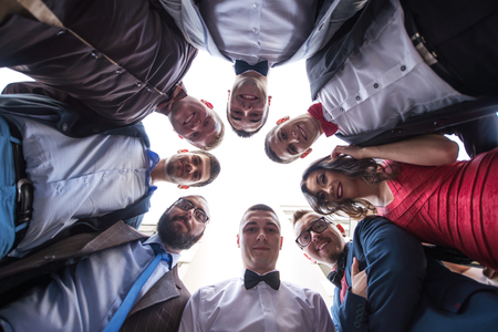 A business team standing in a circle smiling up at the camera. Low angle shot, selective focus.の写真素材