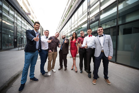 Group of elegant young business men standing and showing thumbs up.