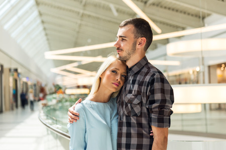 Young happy couple cuddling each other in a shopping mall.の写真素材