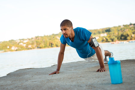 Young male athlete doing push ups next to the river.