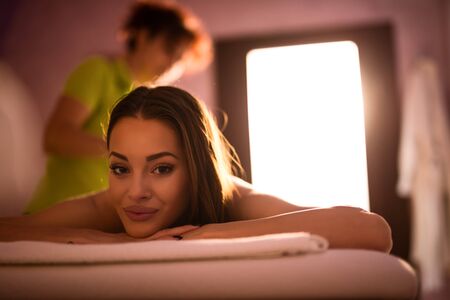 Shot of a beautiful young woman relaxing and waiting for a massage. High ISO, grainy image, natural light only.の写真素材