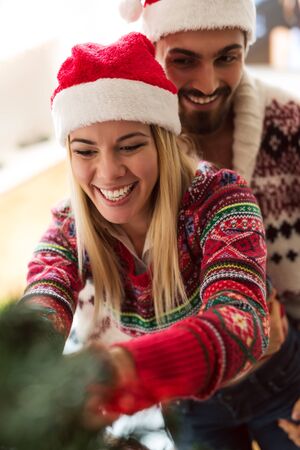 Shot of a young happy couple decorating a Christmas tree. Natural light, selective focusの写真素材