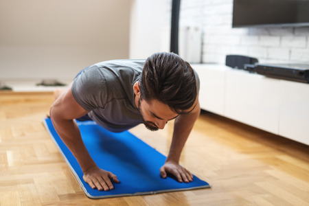Shot of a man doing exercise at home.の写真素材