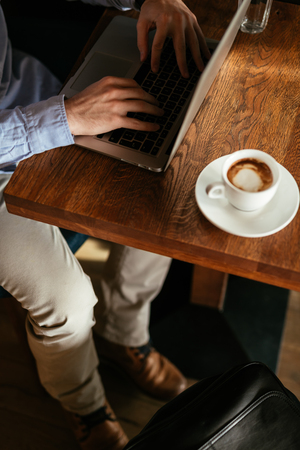 Man typing on a laptop keyboard in a cafe shop.の写真素材