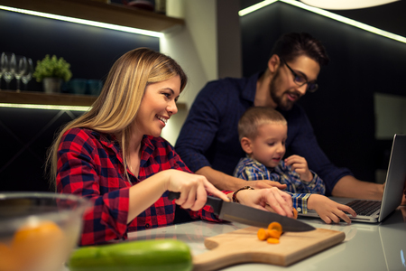 Mother preparing food while dad and son using laptop. Selective focus.の写真素材
