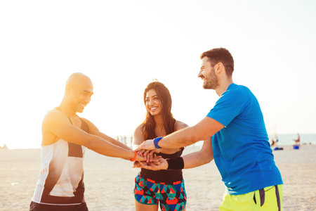 Group of young friends piling their hands together.