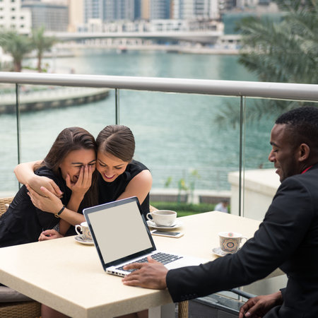 Two woman laughing while having a meeting outdoors.