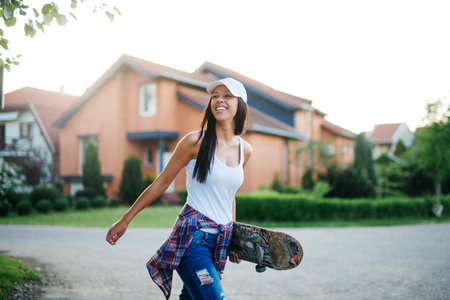 Attractive teenage girl holding a skateboard in the city.の写真素材