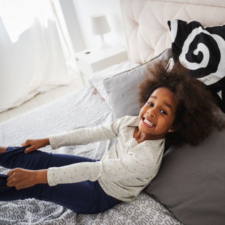Cute little african girl having fun in bed.の写真素材