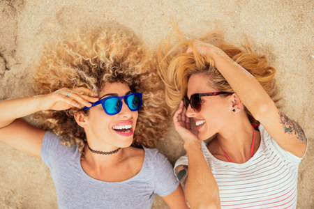 Beautiful happy women lying on the beach together.の写真素材