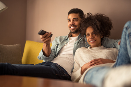 Cropped shot of a young african american couple watching television at homeの写真素材