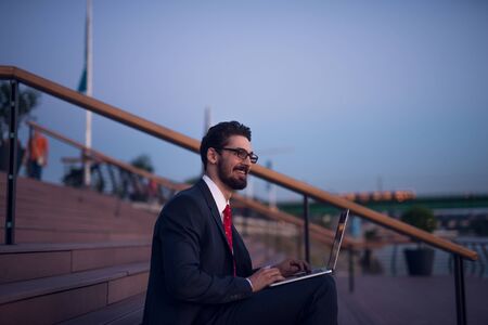 Businessman sitting on a stairs and working on a computer.の写真素材