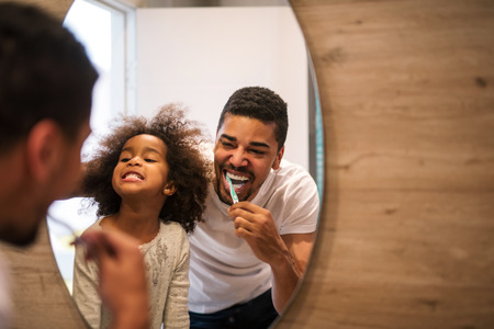 African american girl brushing teeth with dad.の写真素材