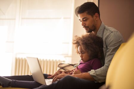 Dad and his little kid watching something on a laptop.の写真素材