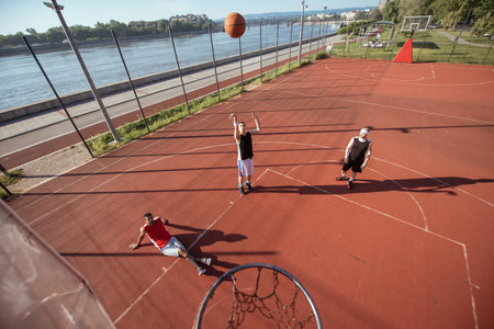 Team of basketball players playing basket outdoors.