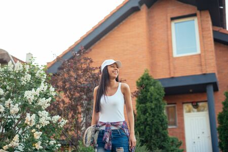 Beautiful young girl carrying skateboard outdoors.の写真素材